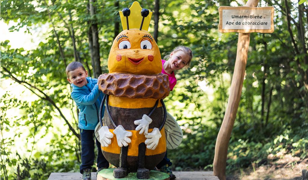 Eine Holzskulptur einer Biene mit zwei Kindern