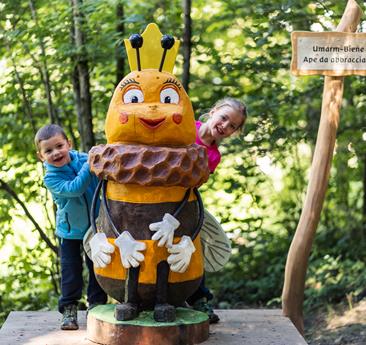 Eine Holzskulptur einer Biene mit zwei Kindern