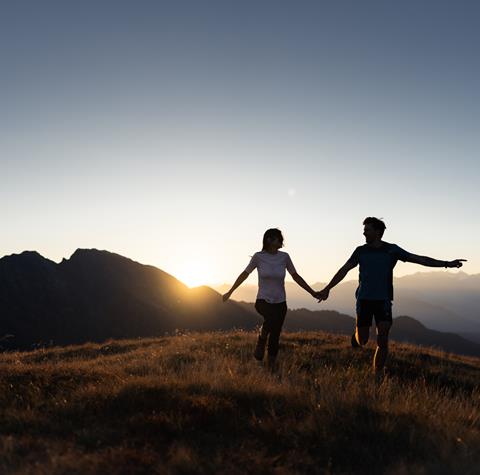 a couple walking on the meadow at sunrise
