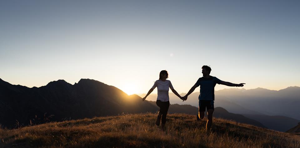 a couple walking on the meadow at sunrise