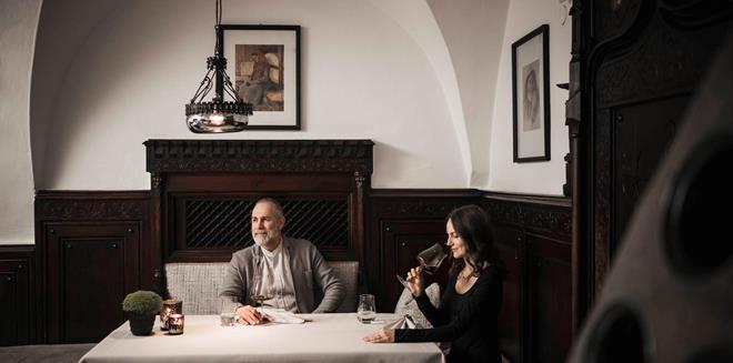 Ein Mann und eine Frau sitzen an einem Tisch und trinken ein Glas Rotwein