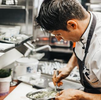 Ein Koch bereitet ein Gericht zu
