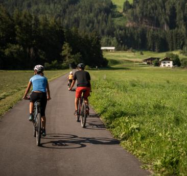 Un uomo, una donna e un bambino con le biciclette su una pista ciclabile