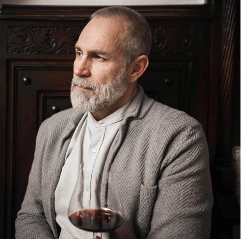 A man is drinking a glass of red wine