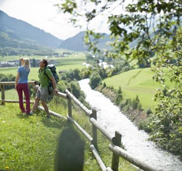 Una coppia si trova accanto a una staccionata sopra un fiume e guarda verso la valle