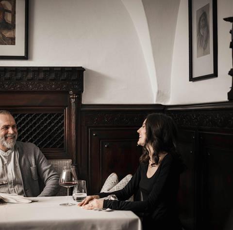 Ein Mann und eine Frau sitzen an einem Tisch und trinken ein Glas Rotwein