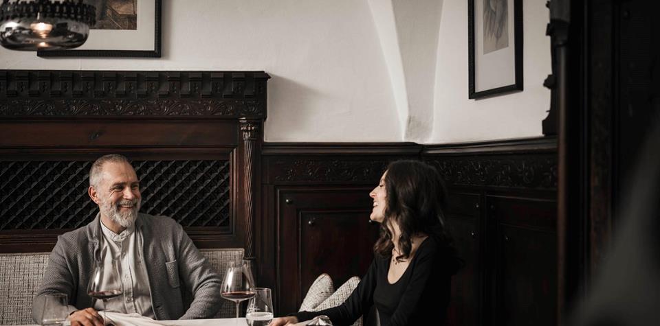 Ein Mann und eine Frau sitzen an einem Tisch und trinken ein Glas Rotwein