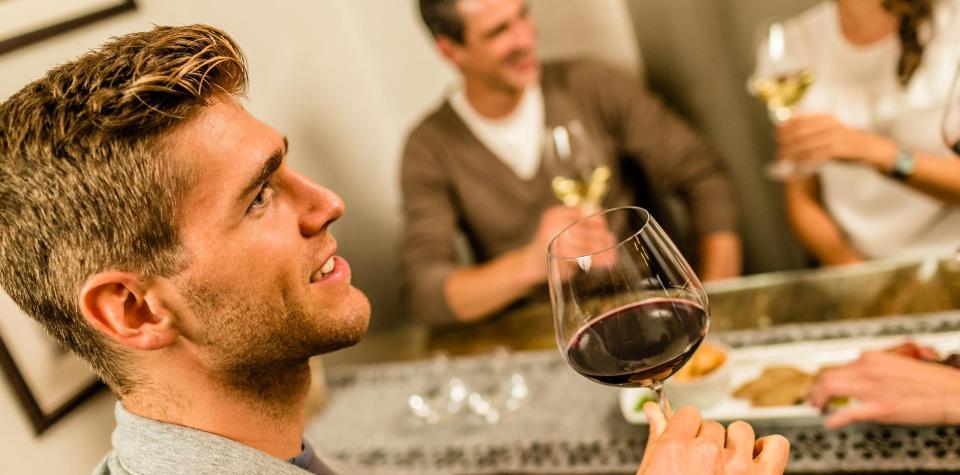 Due uomini e una donna sono seduti a un tavolo e bevono un bicchiere di vino