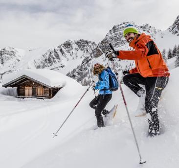 A man and a woman snowshoeing in Ladurns