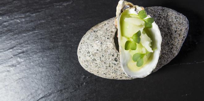 An artfully presented dish in a seashell, served on a stone surface