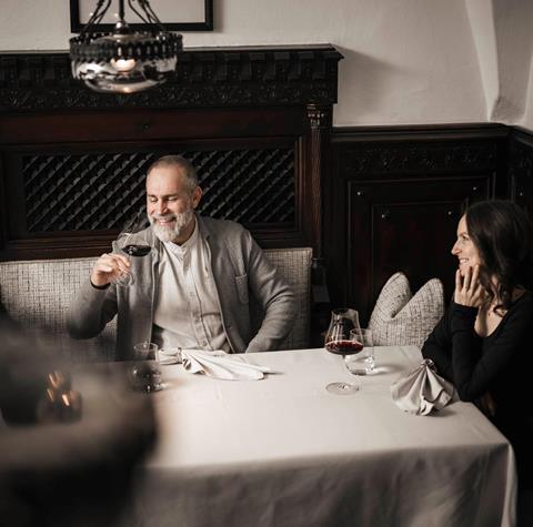 Ein Mann und eine Frau sitzen an einem Tisch und trinken ein Glas Rotwein