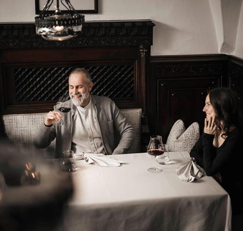 Ein Mann und eine Frau sitzen an einem Tisch und trinken ein Glas Rotwein