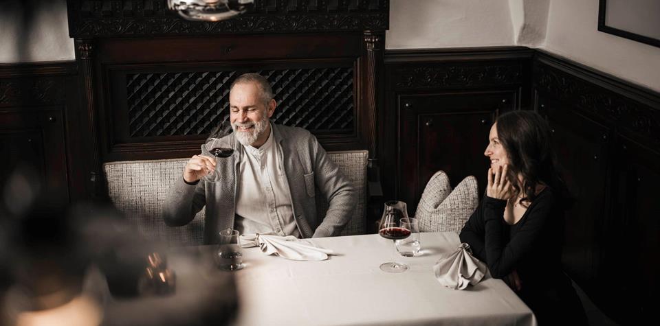 Un uomo e una donna sono seduti a un tavolo e bevono un bicchiere di vino rosso