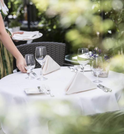 Eine Frau deckt einen Tisch im Garten