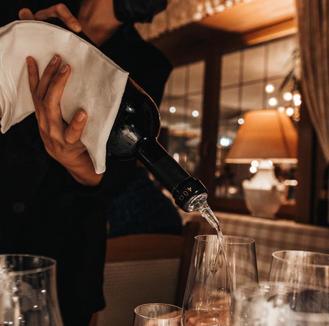 Una sommelier versa un bicchiere di vino