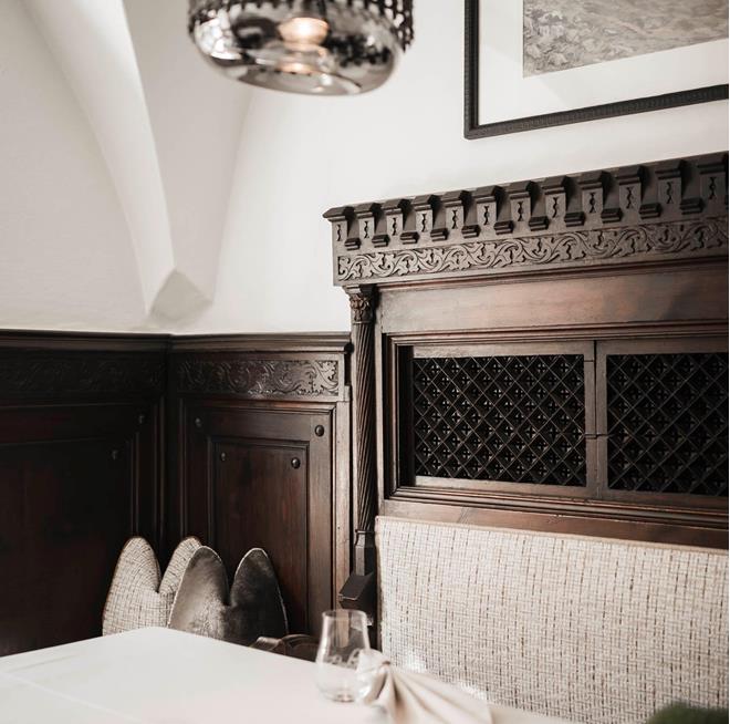 Una tavola elegantemente apparecchiata nella Stube dell’Hotel Stafler, con legno scuro, una panca imbottita e la calda luce delle candele