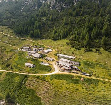 An alpine village lies nestled amid green mountain meadows