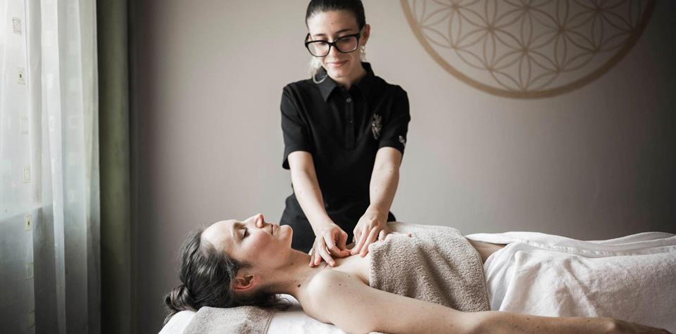 A woman is lying on a lounger and receiving a massage