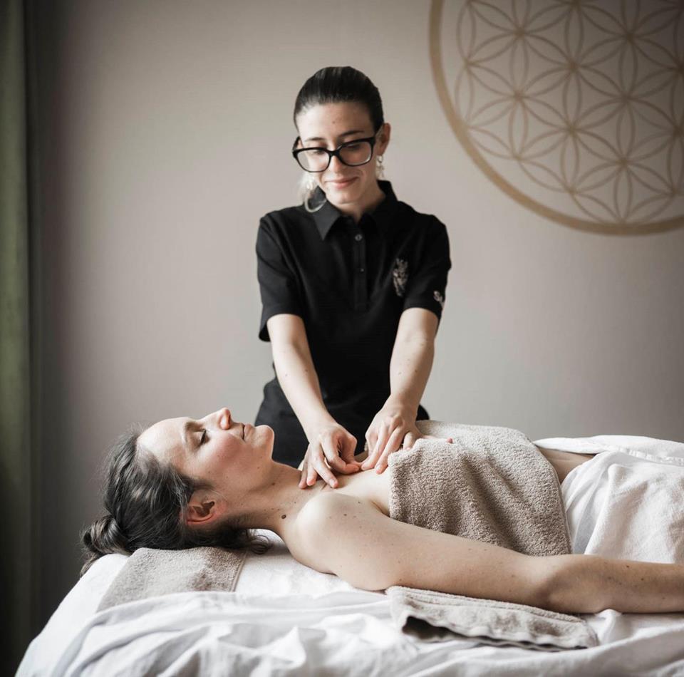 A woman is lying on a lounger and receiving a massage