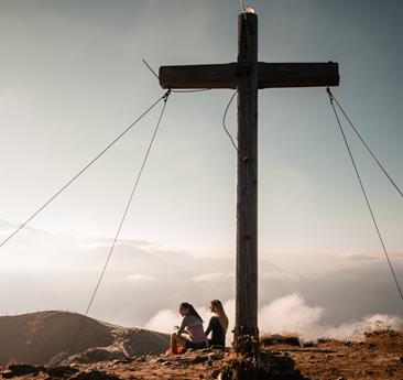 Zwei Frauen sitzen am Gipfelkreuz