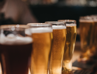 Several glasses of beer are on a wooden table