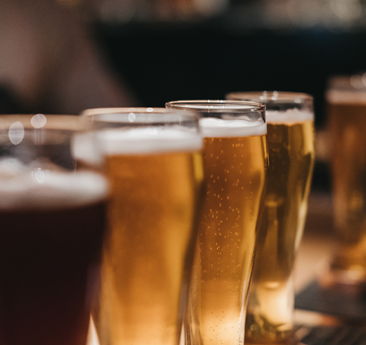 Several glasses of beer are on a wooden table