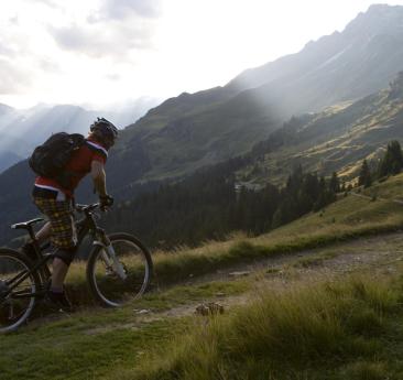 A man with his bicycle on a downhill trail