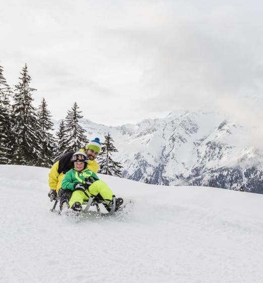 A man and a child sledding in Ladurns