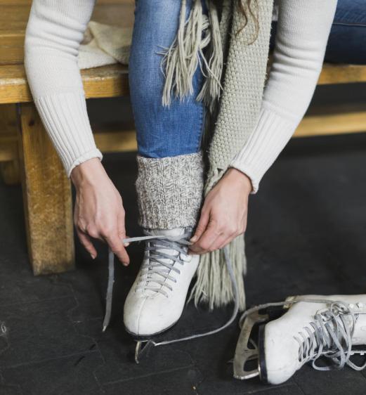 Eine Frau zieht sich Schlittschuhe an
