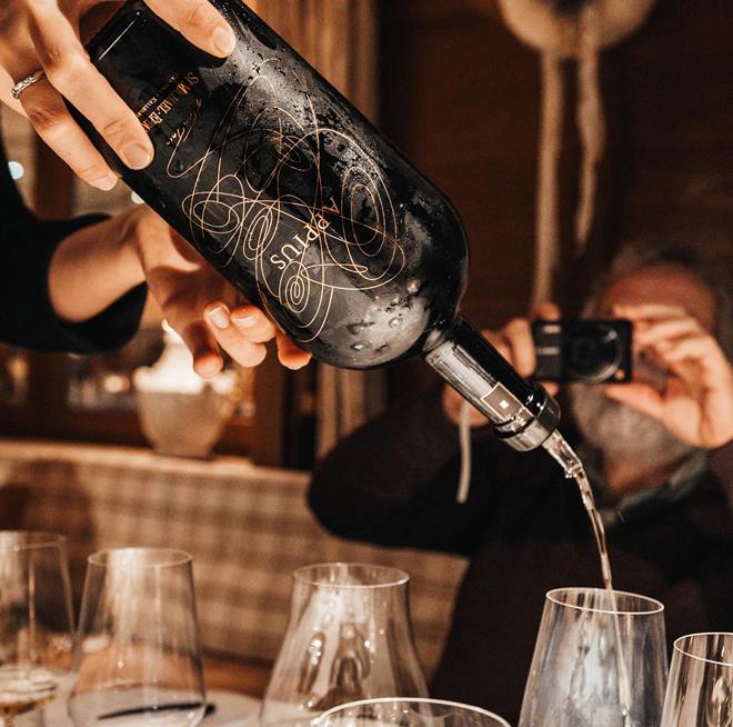 Un sommelier versa un bicchiere di vino bianco