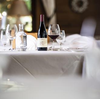 A bottle of wine and a bottle of water with glasses are placed on a table
