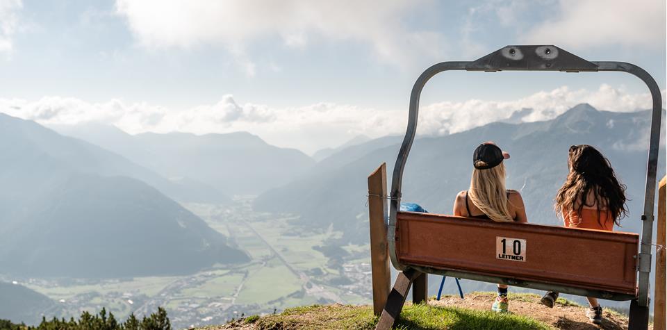 Zwei Wanderinnen sitzen auf einer Bank und genießen die Aussicht