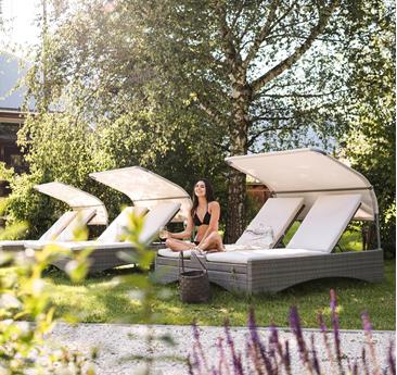 A woman is lying on a deck chair in the garden