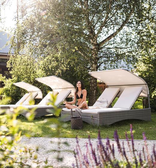 A woman is lying on a deck chair in the garden