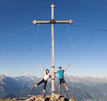 Un uomo e una donna stanno in piedi presso la croce di vetta