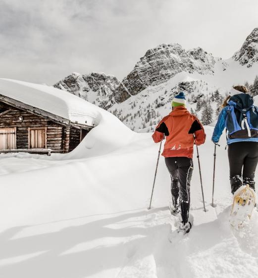 A man and a woman snowshoeing in Ladurns