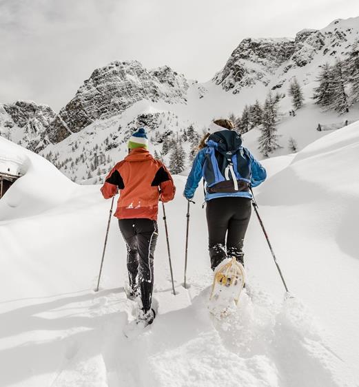 A man and a woman snowshoeing in Ladurns