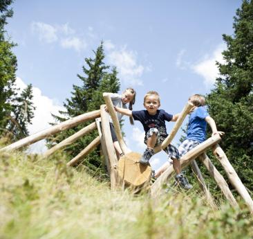 Un bambino arrampica su un ragno di legno nel mondo delle avventure in montagna di Racines