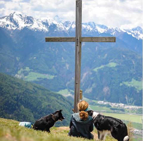 Frau mit Hunden am Gipfelkreuz