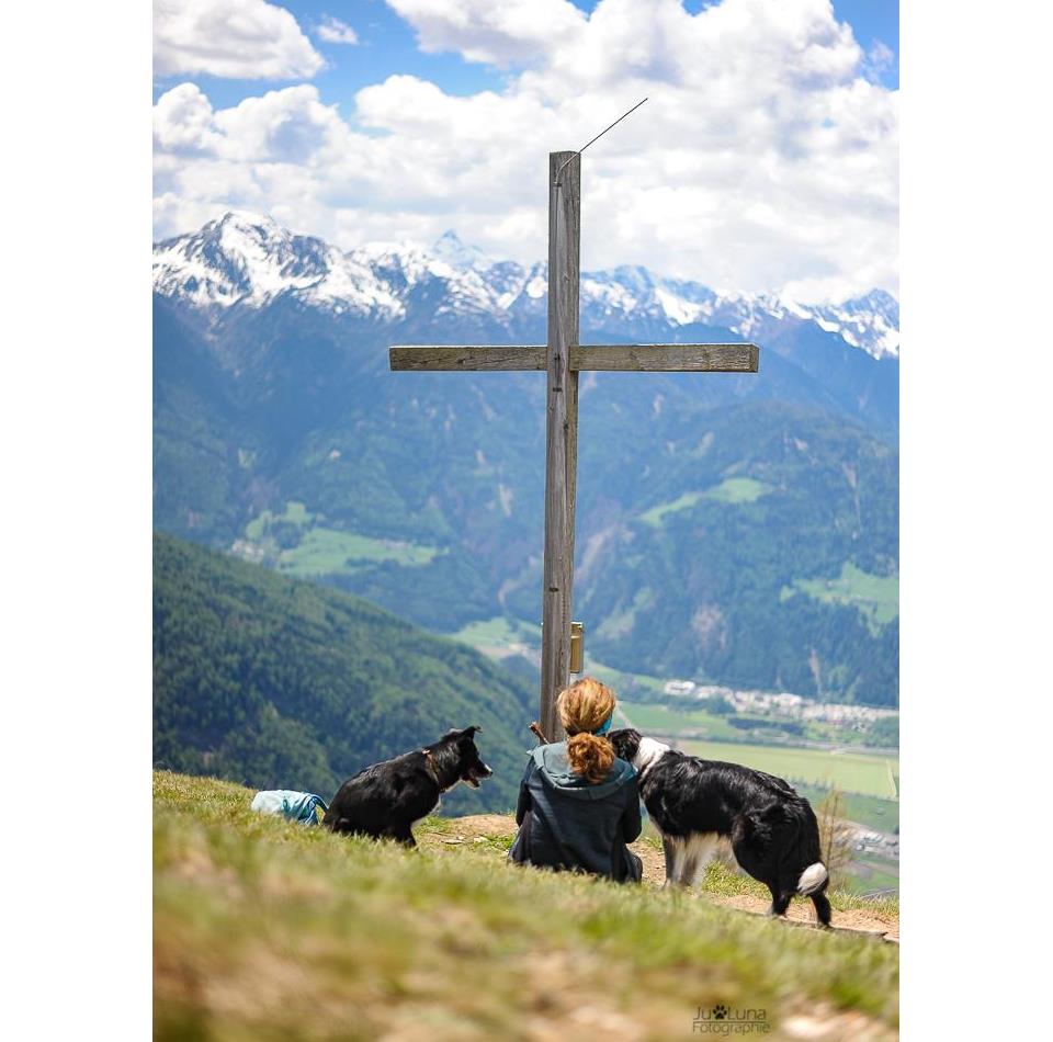Frau mit Hunden am Gipfelkreuz