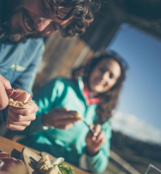 A man and a woman are eating South Tyrolean Schüttelbrot with speck