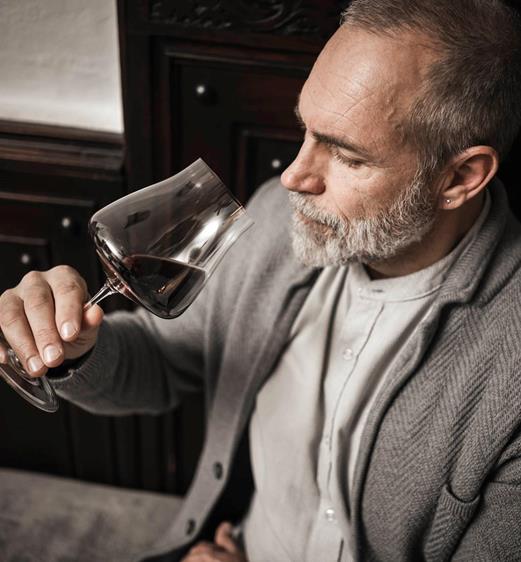 A man is drinking a glass of red wine