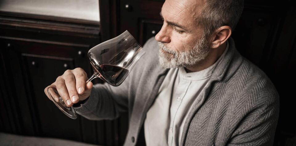 A man is drinking a glass of red wine
