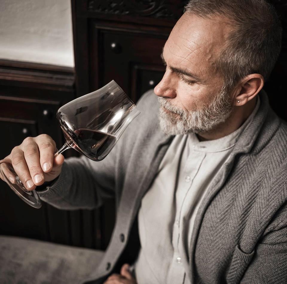 Un uomo beve un bicchiere di vino rosso