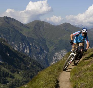 A man with his bicycle on a downhill trail