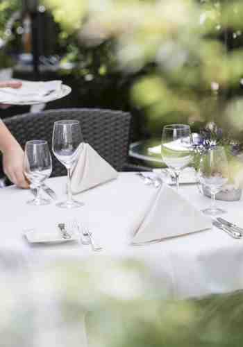 Eine Frau deckt einen Tisch im Garten